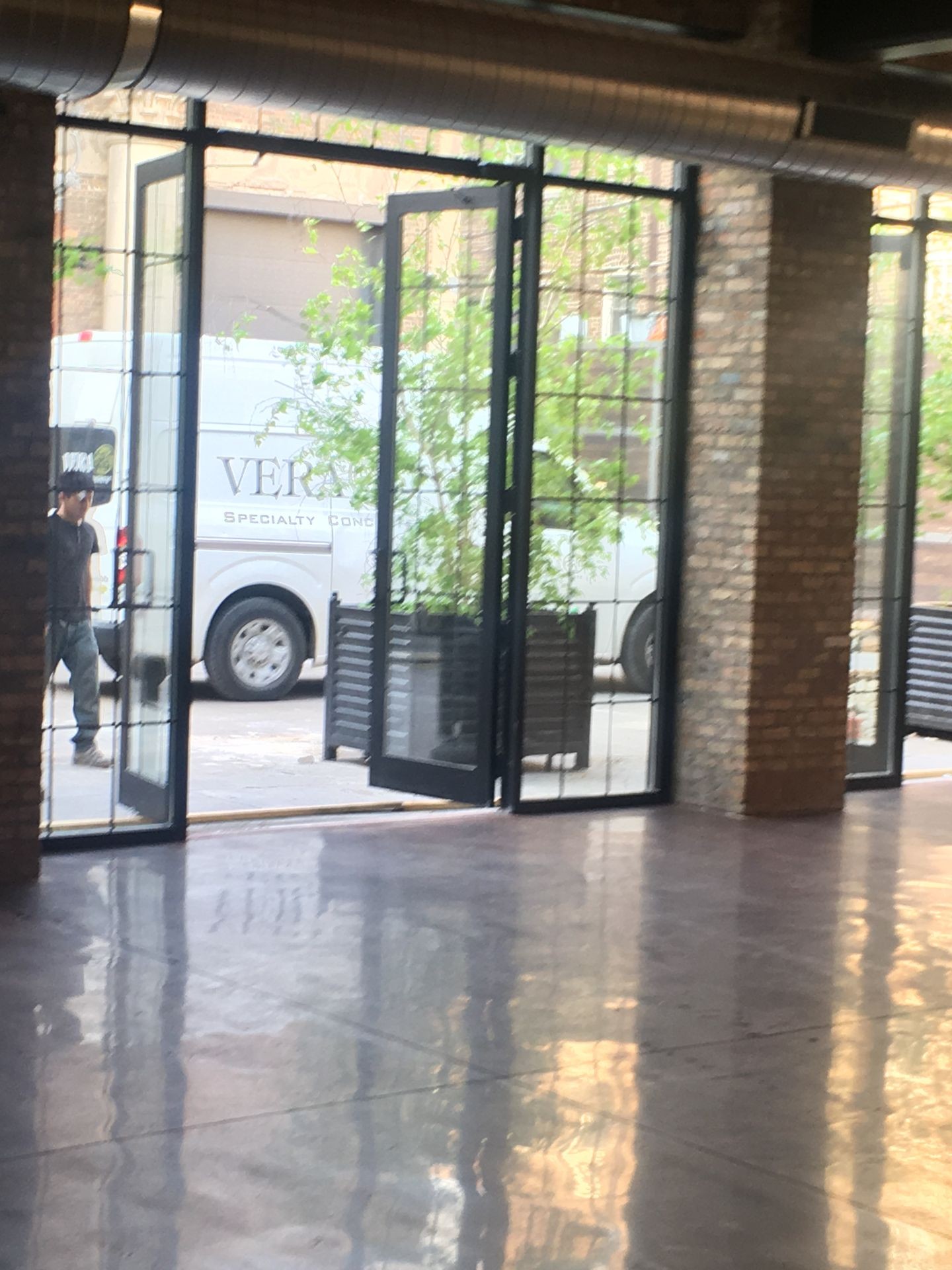 Open glass doors leading outside, with a white van parked and a person walking nearby.