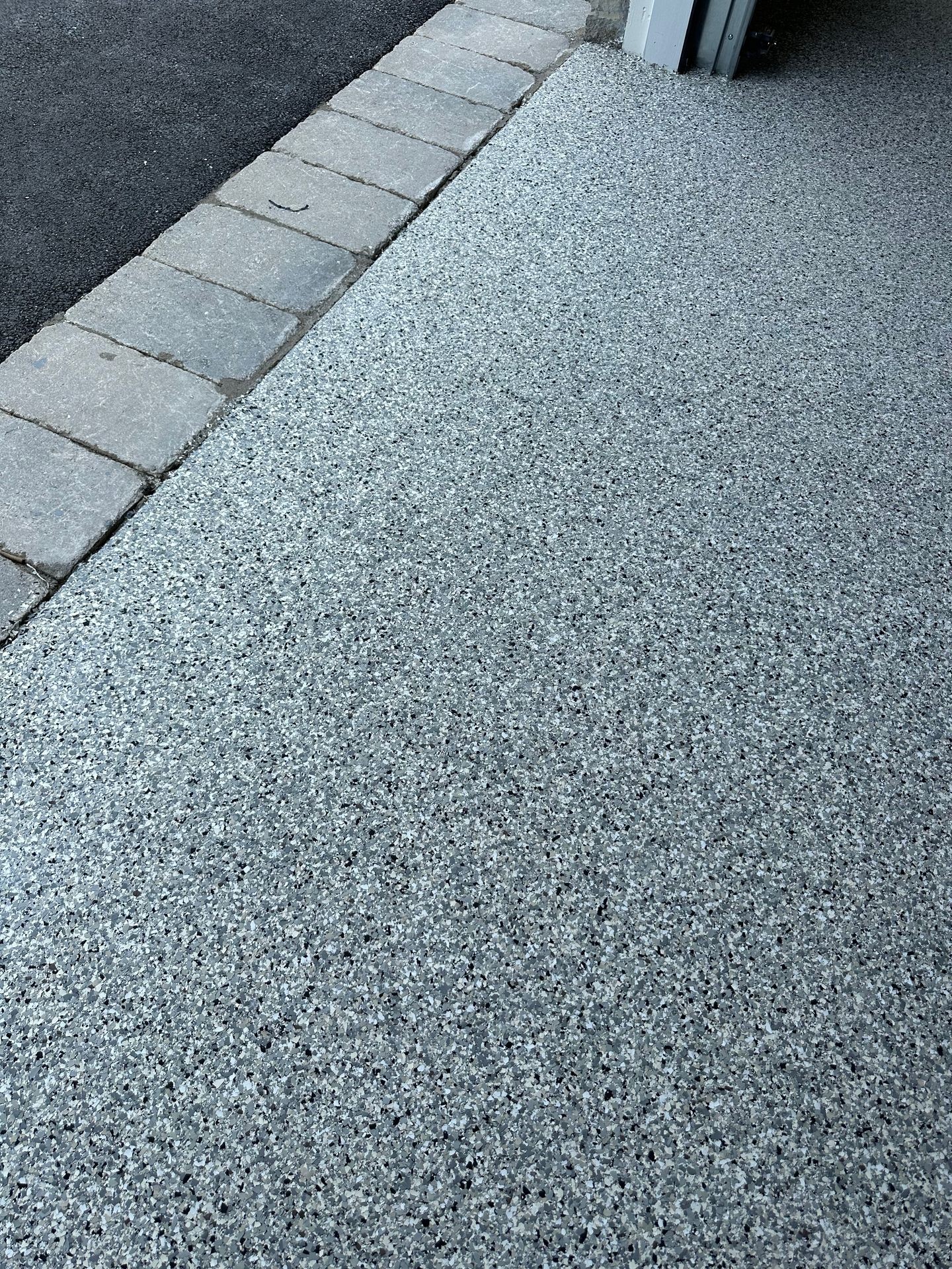 Textured epoxy garage floor with a border of stone pavers.